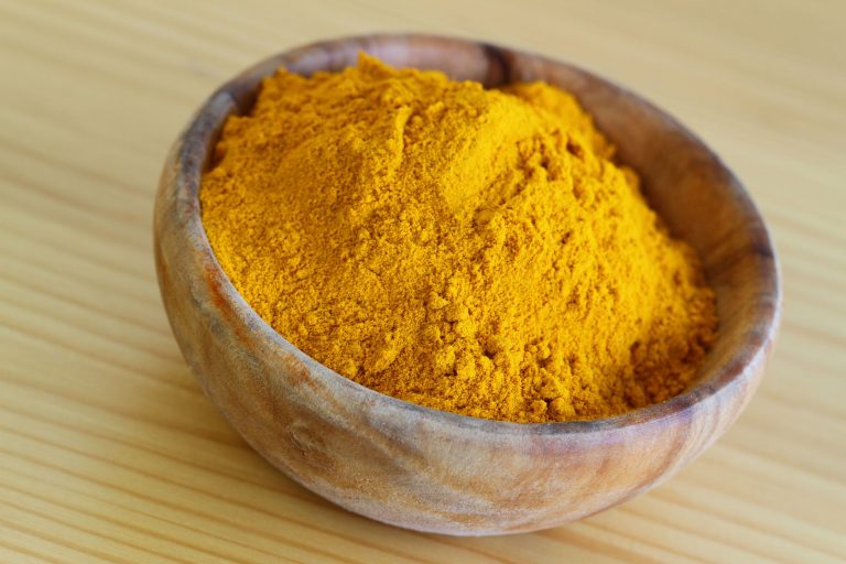 28957780 - tumeric powder in wooden bowl, close up