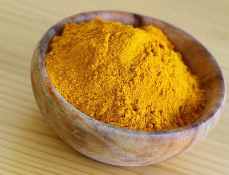 28957780 - tumeric powder in wooden bowl, close up
